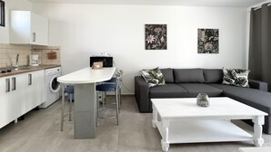 Et moderne køkken med spiseplads, en grå sofa med mønstrede puder og et hvidt sofabord.