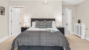 Een slaapkamer met een bed, nachtkastjes, een radiator en een deur.