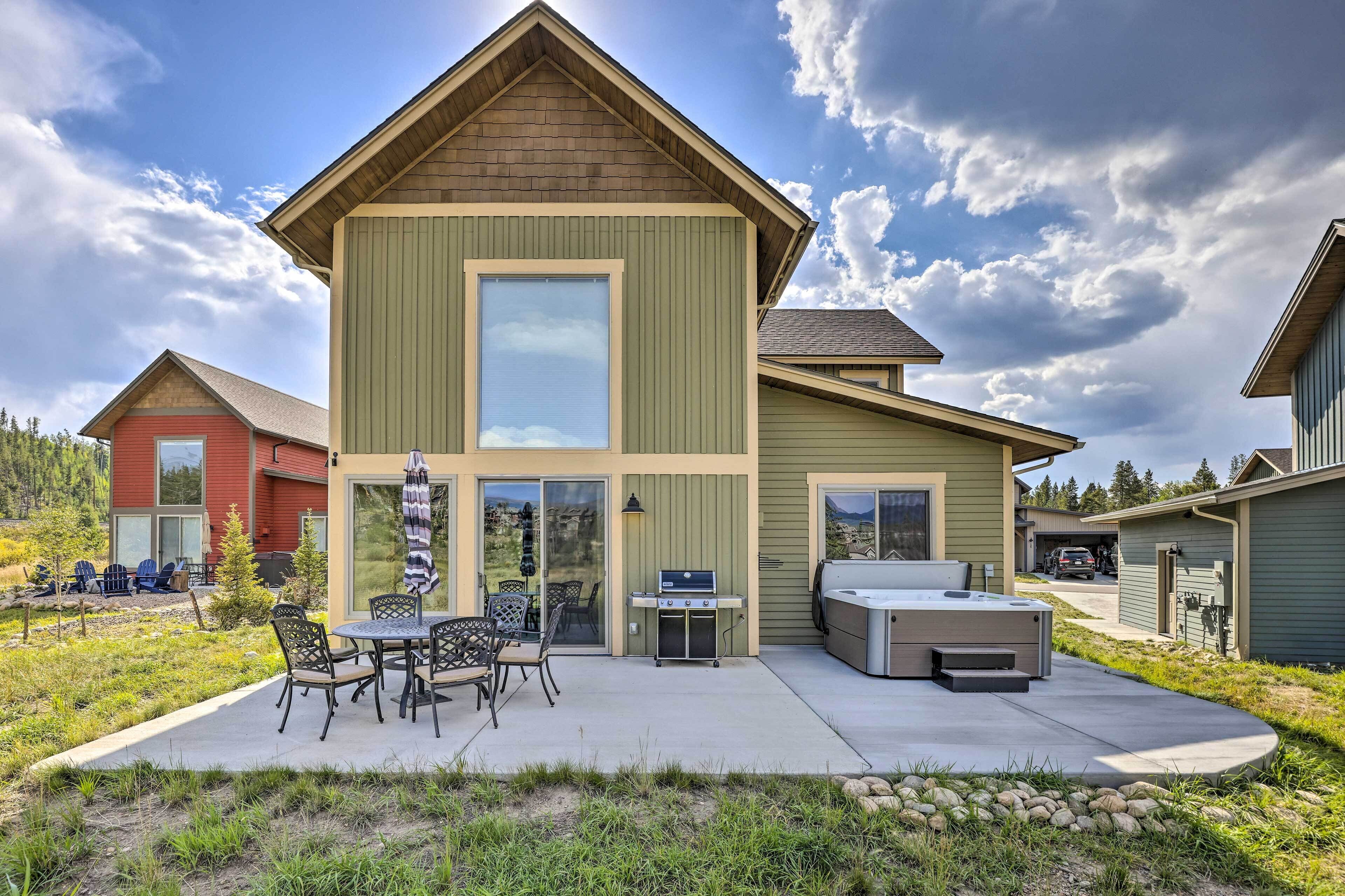 Une maison à deux étages dotée d’un patio comprenant un barbecue et un espace salon extérieur.