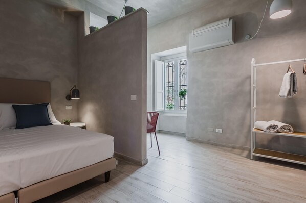 Une chambre à coucher moderne, avec un lit, une table de chevet, une lampe et une vue sur l’extérieur par une fenêtre.