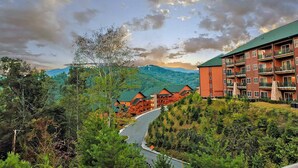 A lodge with multiple-story buildings, a winding road, and a mountainous backdrop.