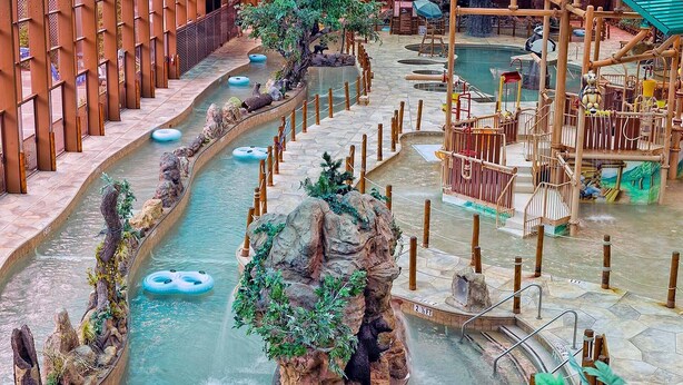 A water park with multiple water slides, a bear statue, and a wooden play structure.