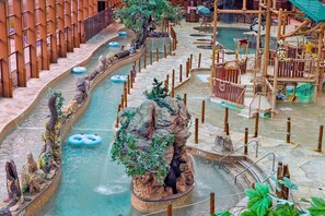 A water park with multiple water slides, a bear statue, and a wooden play structure.
