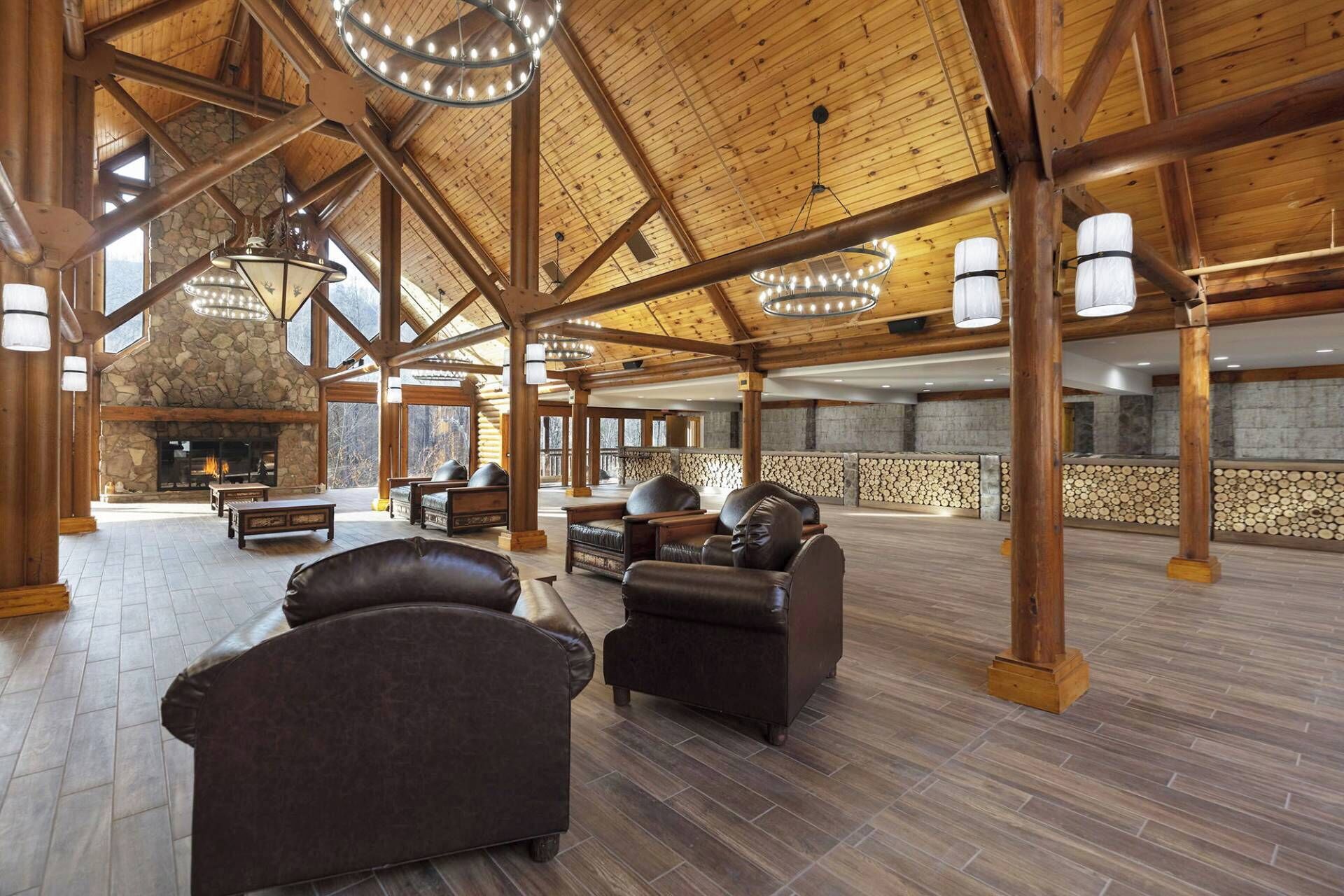 A spacious lobby with a stone fireplace, leather sofas, and a high wooden ceiling with exposed beams.