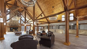 A spacious lobby with a stone fireplace, leather sofas, and a high wooden ceiling with exposed beams.