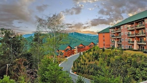 A lodge with multiple-story buildings, a winding road, and a mountainous backdrop.