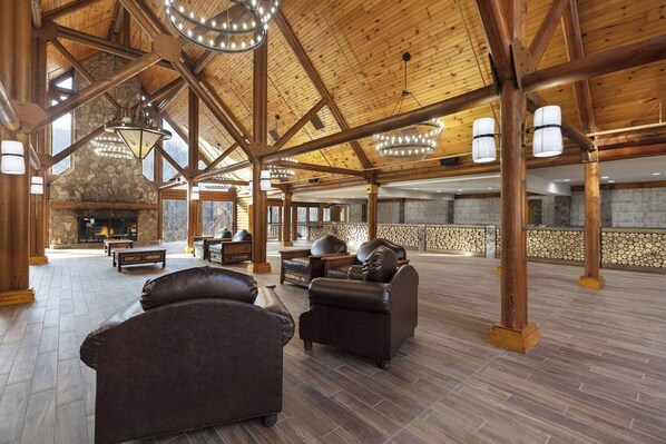 A spacious lobby with a stone fireplace, leather sofas, and a high wooden ceiling with exposed beams.