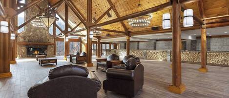 A spacious lobby with a stone fireplace, leather sofas, and a high wooden ceiling with exposed beams.