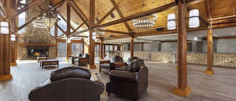 A spacious lobby with a stone fireplace, leather sofas, and a high wooden ceiling with exposed beams.