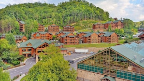 A lodge with multiple wooden buildings, a road, and a large glass structure. - Excellent Location - Smoky Mountain Resort - Family Friendly - Waterpark - Sleeps 16! (Gatlinburg)