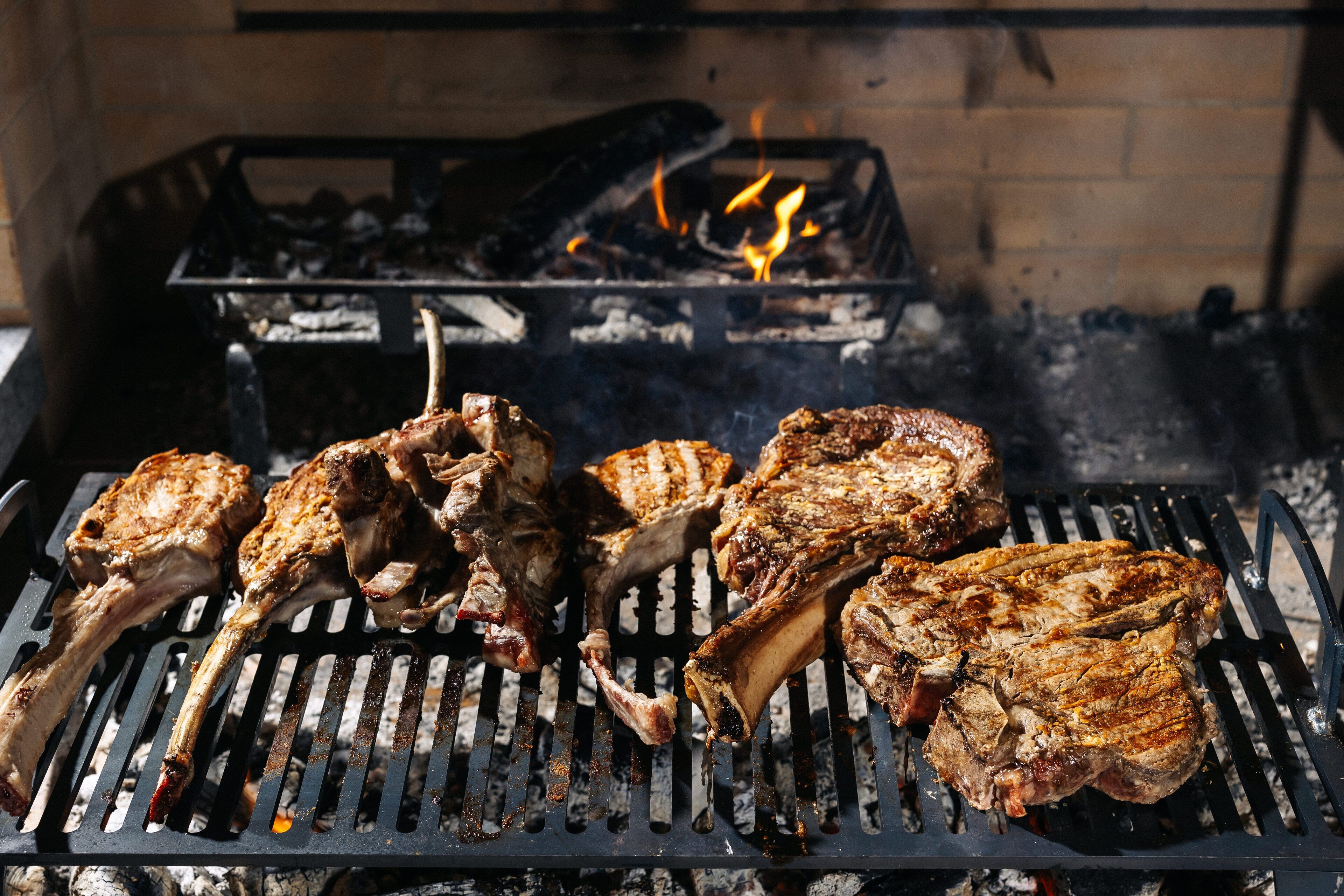 A grill with several pieces of meat being cooked over an open flame.