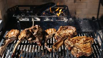 A grill with several pieces of meat being cooked over an open flame.