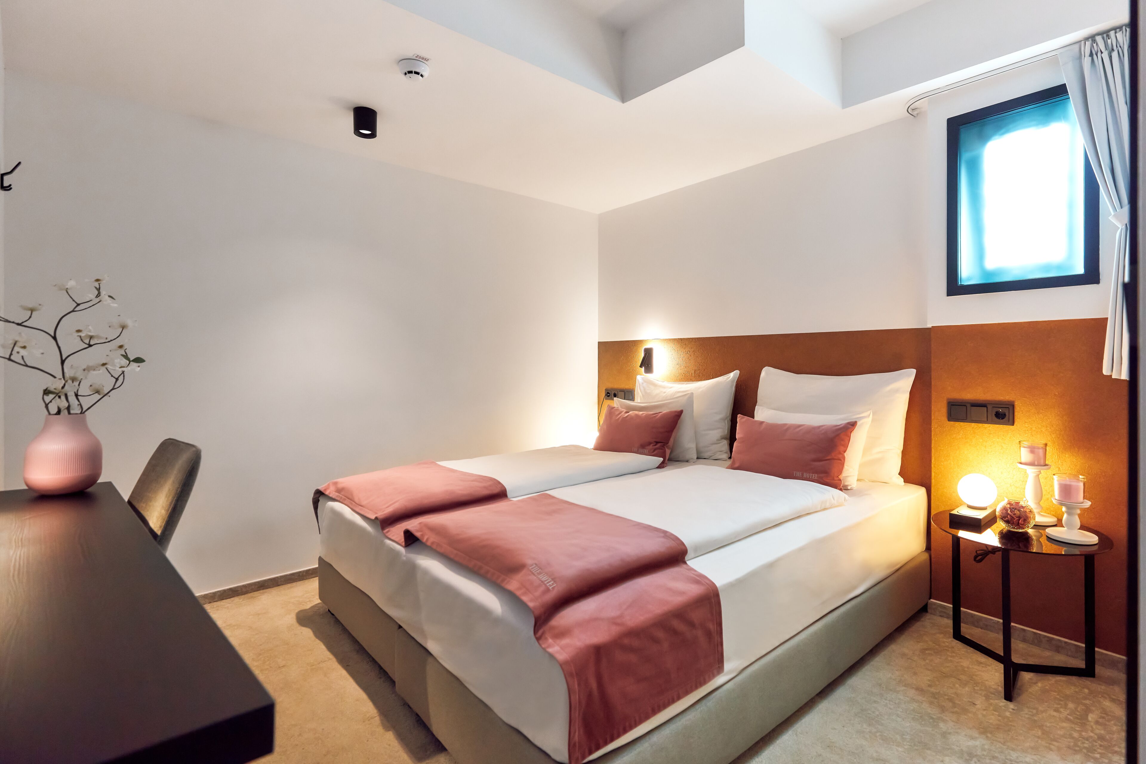 Ein Hotelzimmer mit Bett, Nachttisch und Fenster.