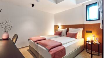 Ein Hotelzimmer mit Bett, Nachttisch und Fenster.