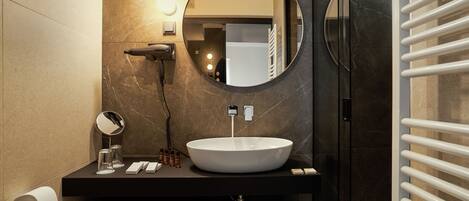 Une salle de bain moderne avec un miroir rond, un lavabo blanc et un porte-serviettes.