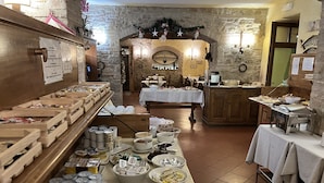Montaje de bufé con diferentes alimentos y bebidas, cajas de madera y un fondo de pared de piedra.