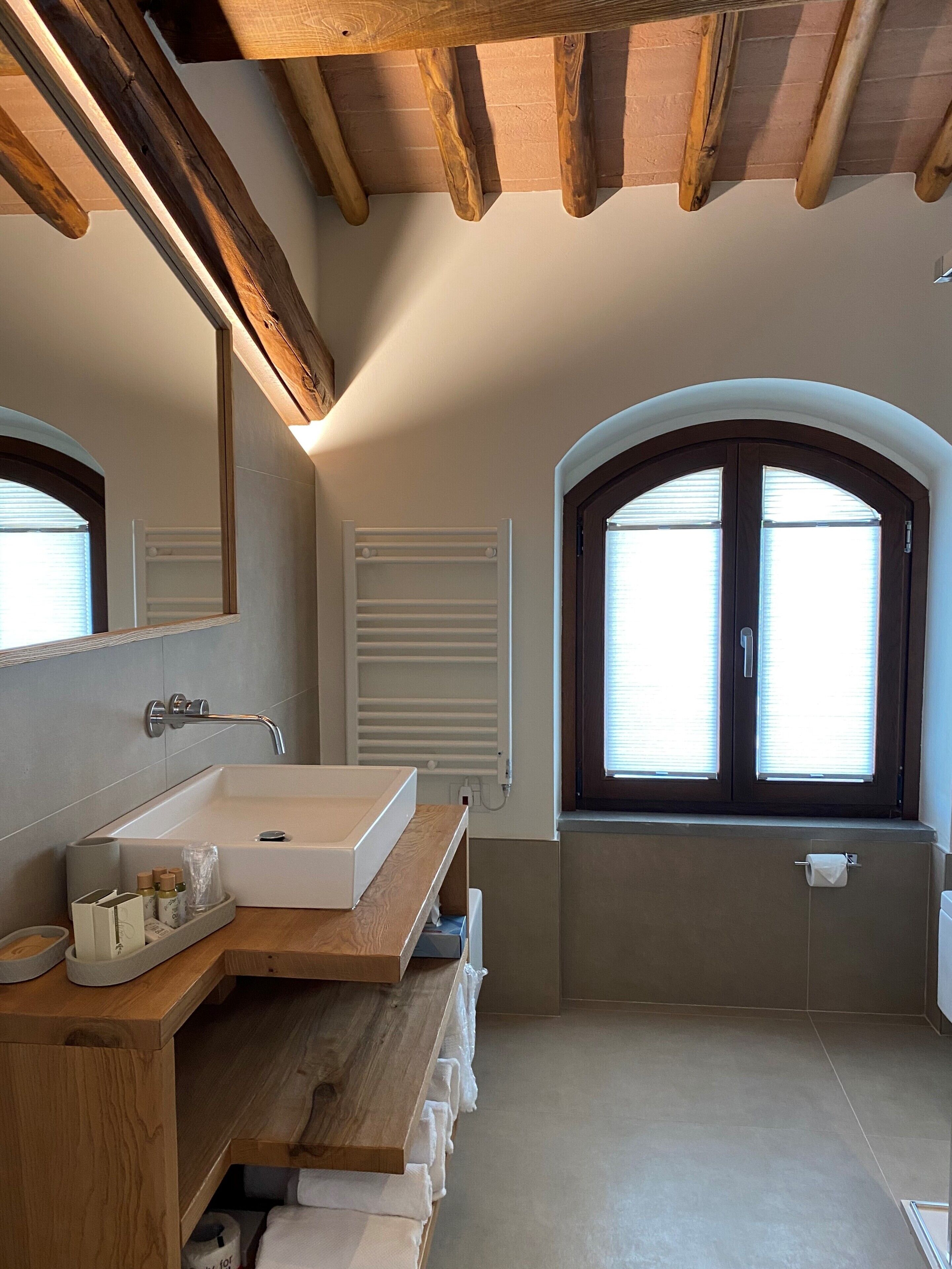 A modern bathroom with a wooden vanity, a large mirror, and a bathtub.