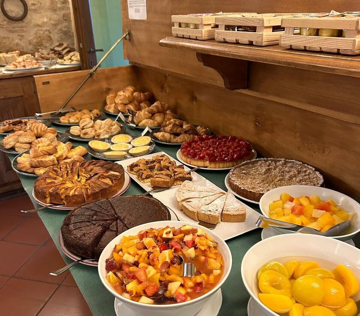 A buffet with various baked goods, including cakes, pies, and pastries, as well as fruit and dessert bowls.