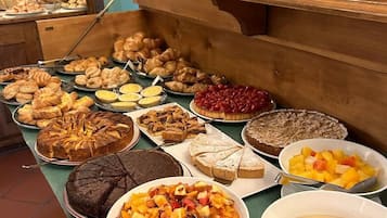 A buffet with various baked goods, including cakes, pies, and pastries, as well as fruit and dessert bowls.