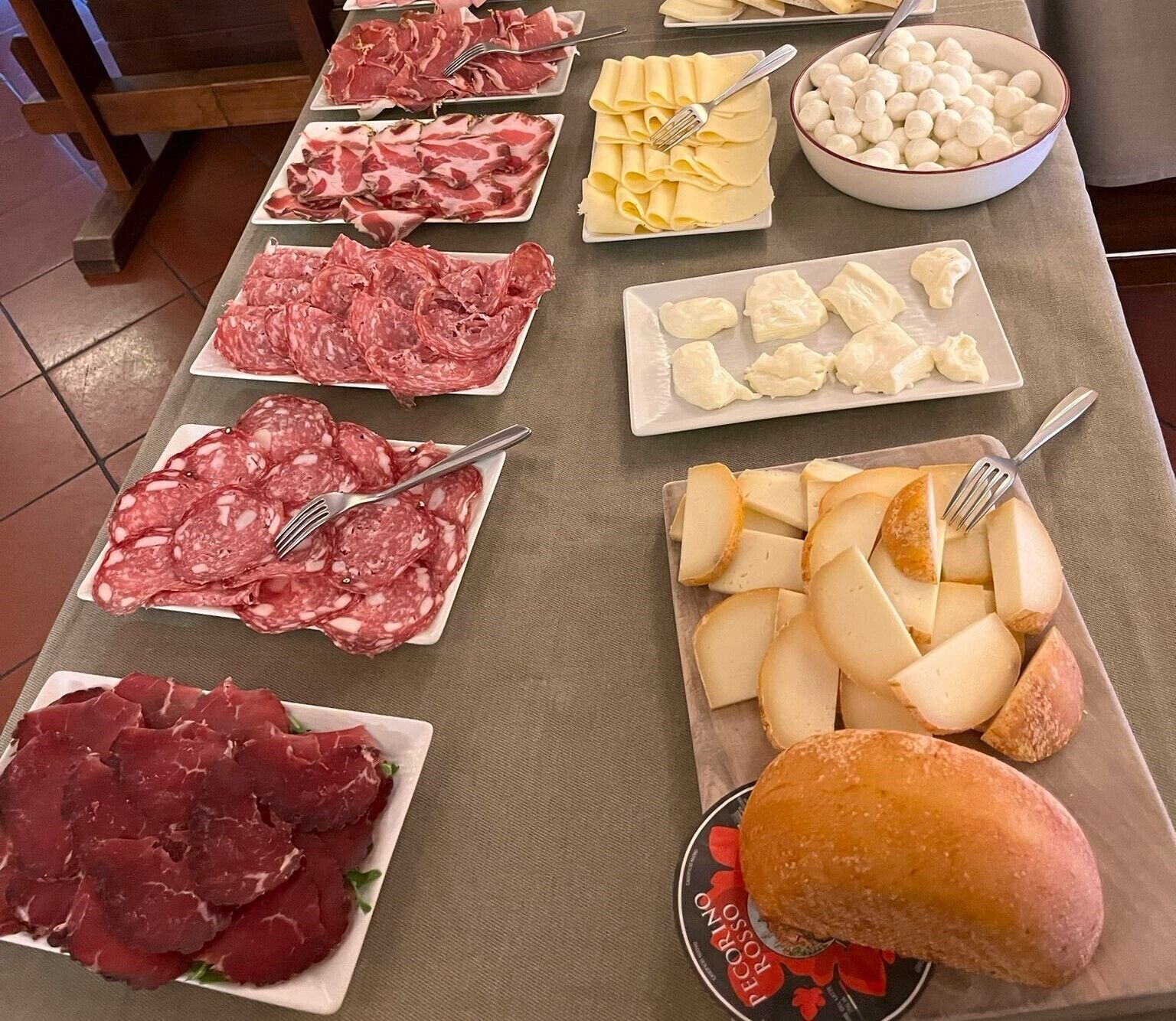 A table with various types of cured meats, cheeses, and a baguette.