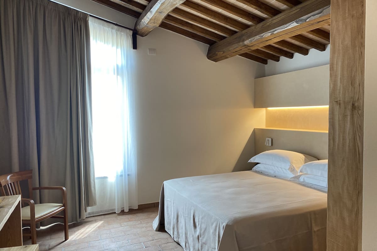 A bedroom with a bed, wooden headboard, and a desk with a chair.