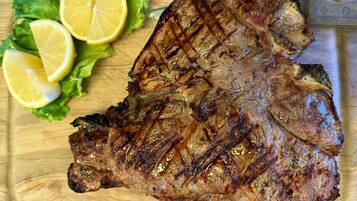 Un steak grillé, garni de tranches de citron et de laitue, présenté sur une planche à découper en bois.