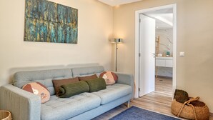 A modern living room with a grey sofa, a floor lamp, and a painting on the wall.