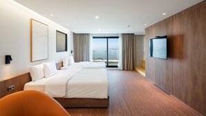A modern hotel room with a large bed, a TV, and a view of the city. - Hotel Cielo (Siheung)