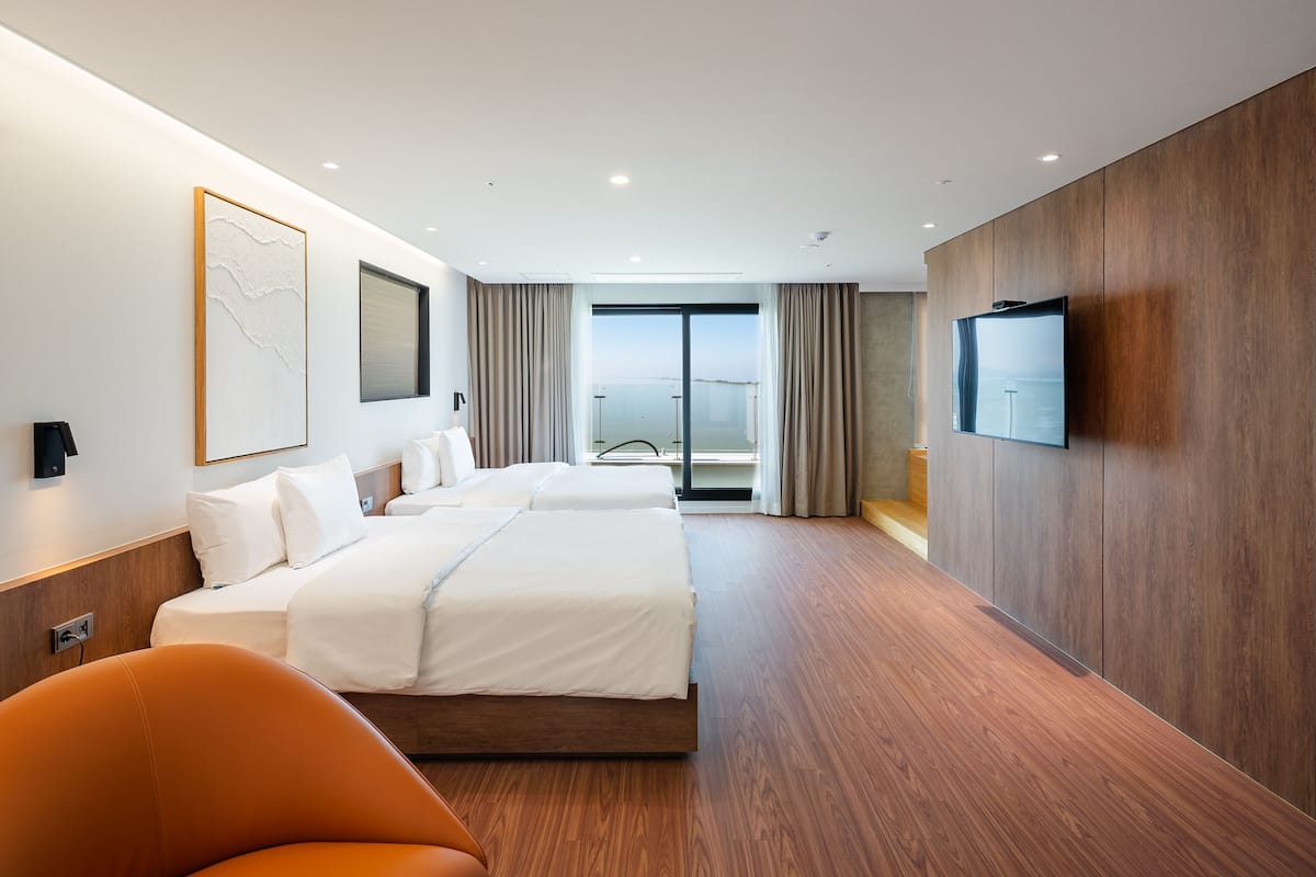 A modern hotel room with a large bed, a TV, and a view of the city.