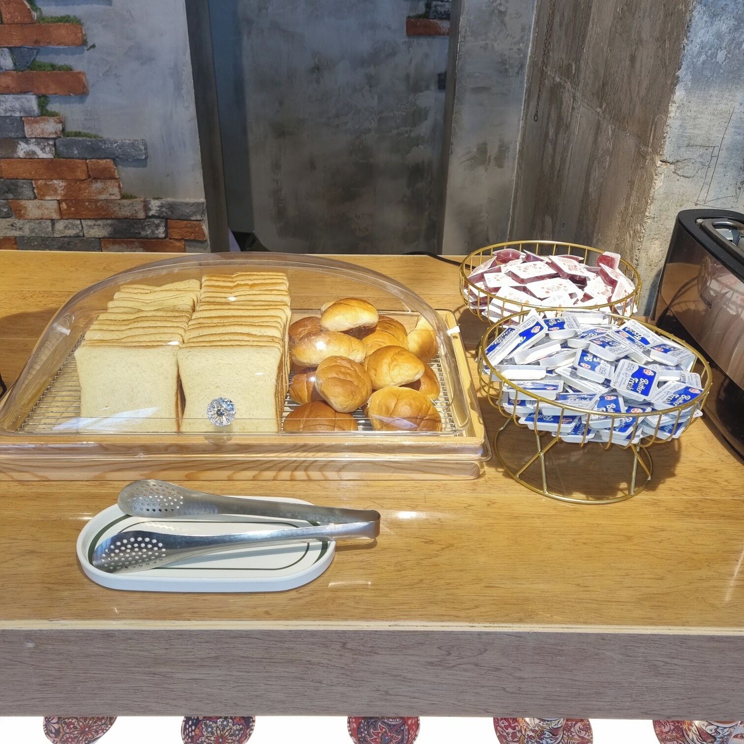 Un présentoir de petit-déjeuner avec du pain, des viennoiseries et des produits emballés, le tout disposé sur un comptoir en bois.