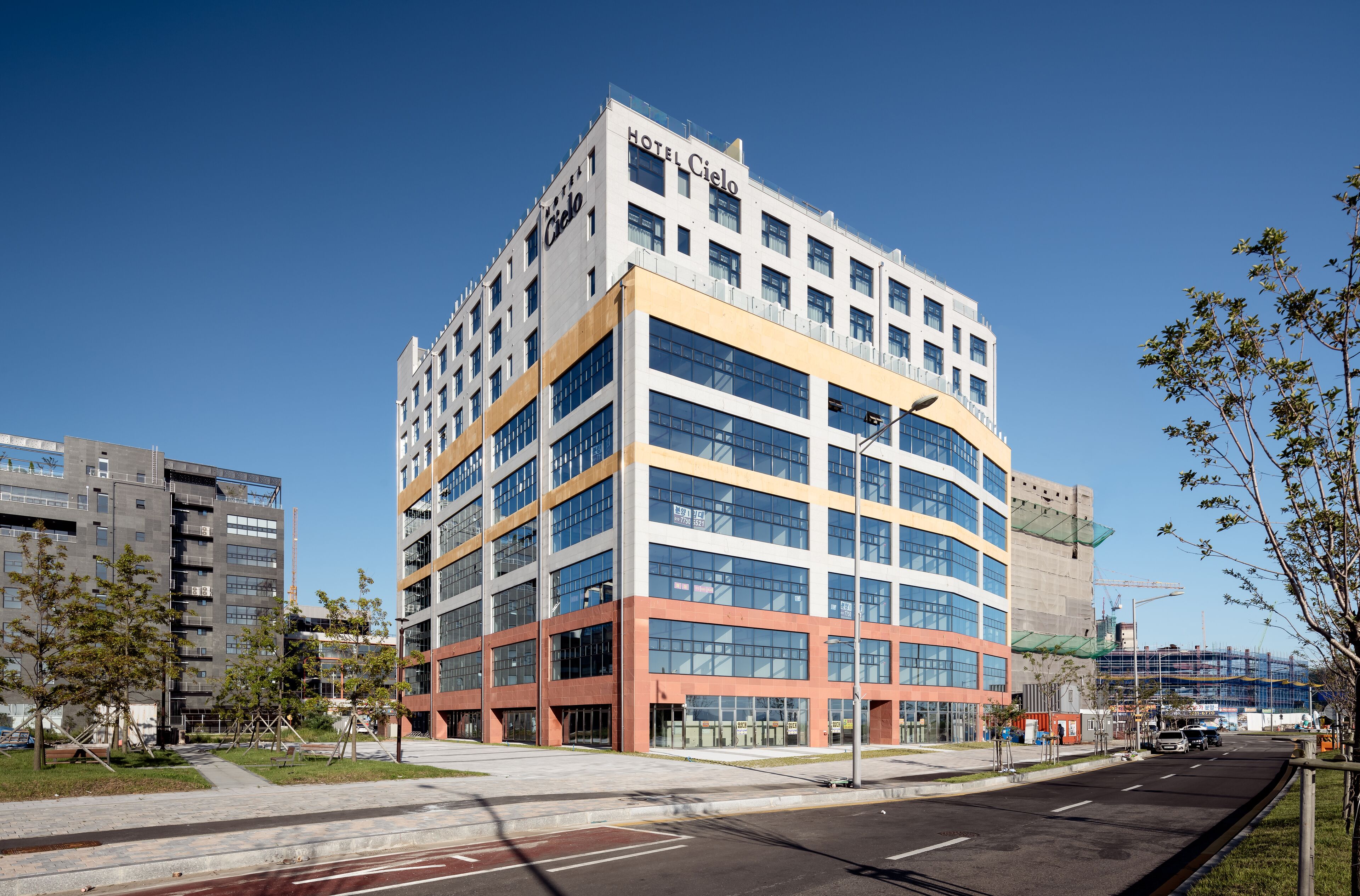 A modern hotel with a curved facade, multiple floors, and large windows.