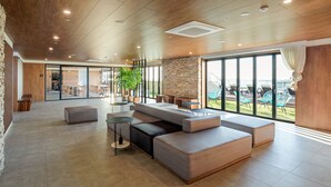 A spacious lobby with a modern design, featuring a large seating area, a stone accent wall, and large windows offering a view of the outdoors. - Hotel Cielo (Siheung)