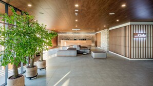 A modern hotel lobby with a reception desk, seating area, and potted plants. - Hotel Cielo (Siheung)