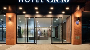 The entrance of HOTEL Cielo with a modern design, featuring glass doors, a reception area, and a visible elevator. - Hotel Cielo (Siheung)