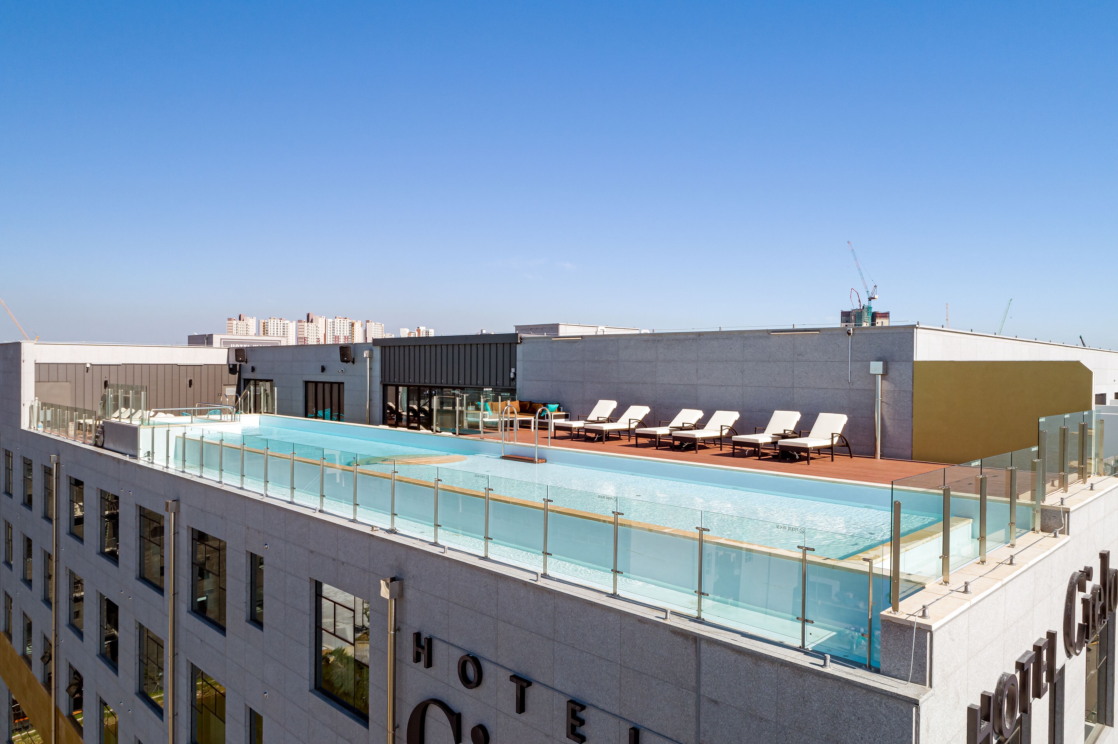 Una piscina en la azotea con sillones de descanso y una vista despejada del horizonte de la ciudad.