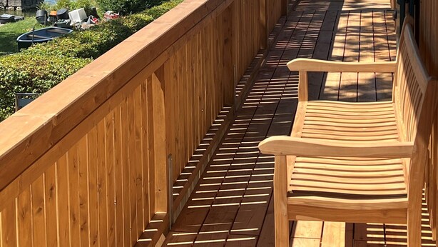 Una terraza de madera con vista a un lago y veleros.