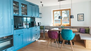 Una cocina moderna con armarios azules, una mesa de comedor de madera y dos sillas.