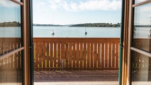 Vista desde una terraza de madera sobre un lago tranquilo con veleros.