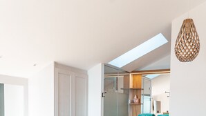 Een moderne slaapkamer met een dakraam, houten plafond en een grote spiegel boven het bed.