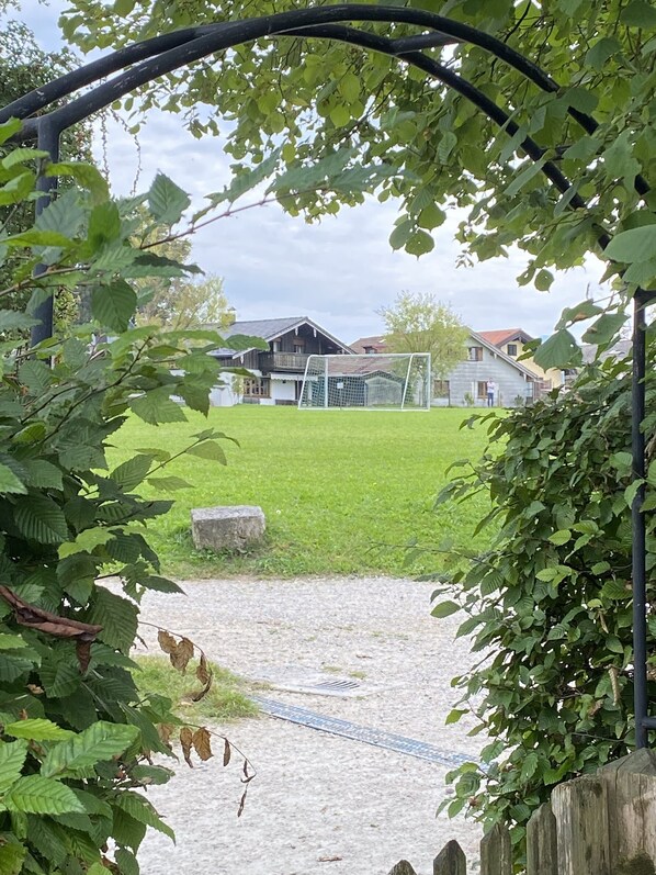 A pathway leading to a building with a metal gate and a grassy area.