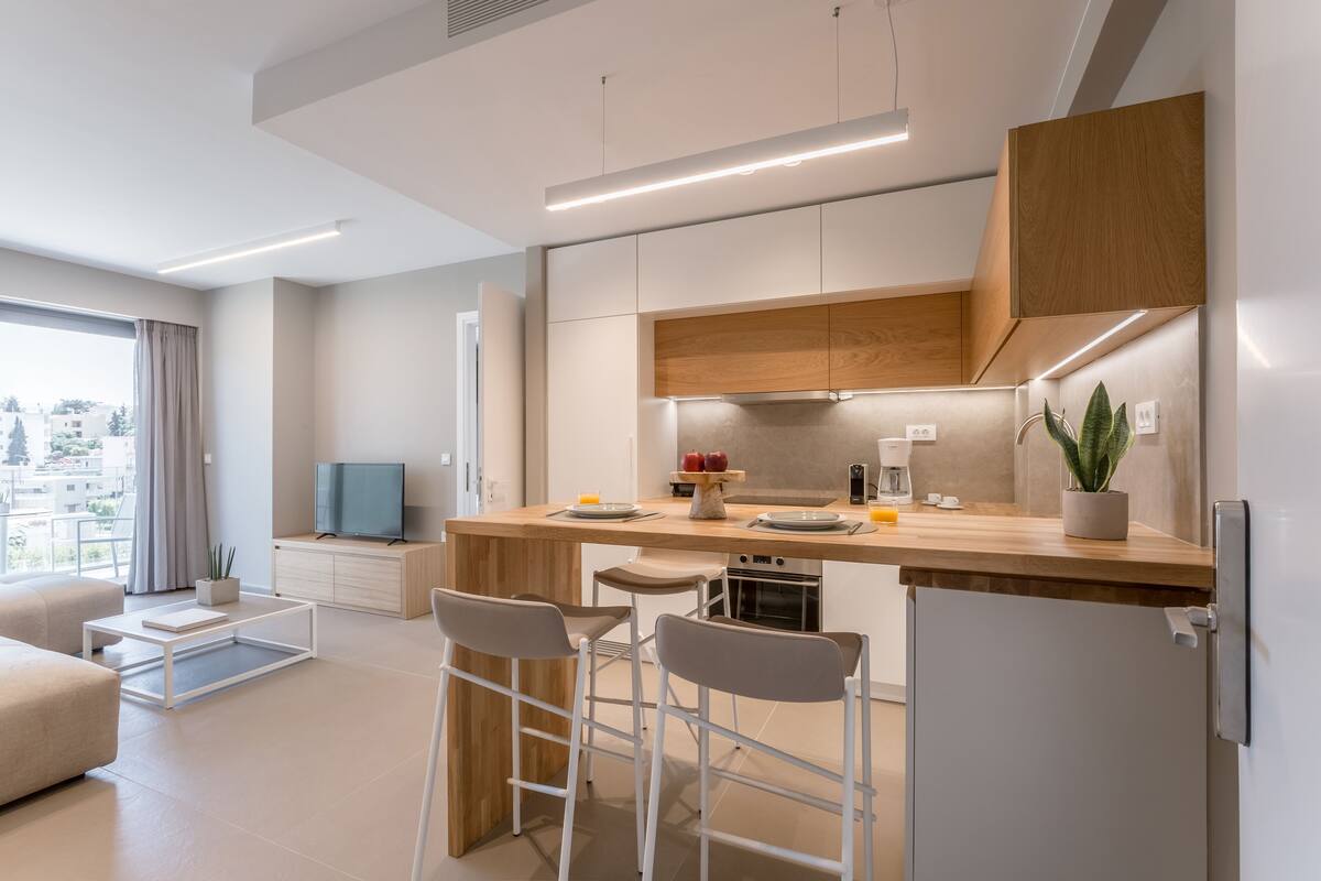 Una cocina moderna con encimera de madera, taburetes de bar y horno empotrado.
