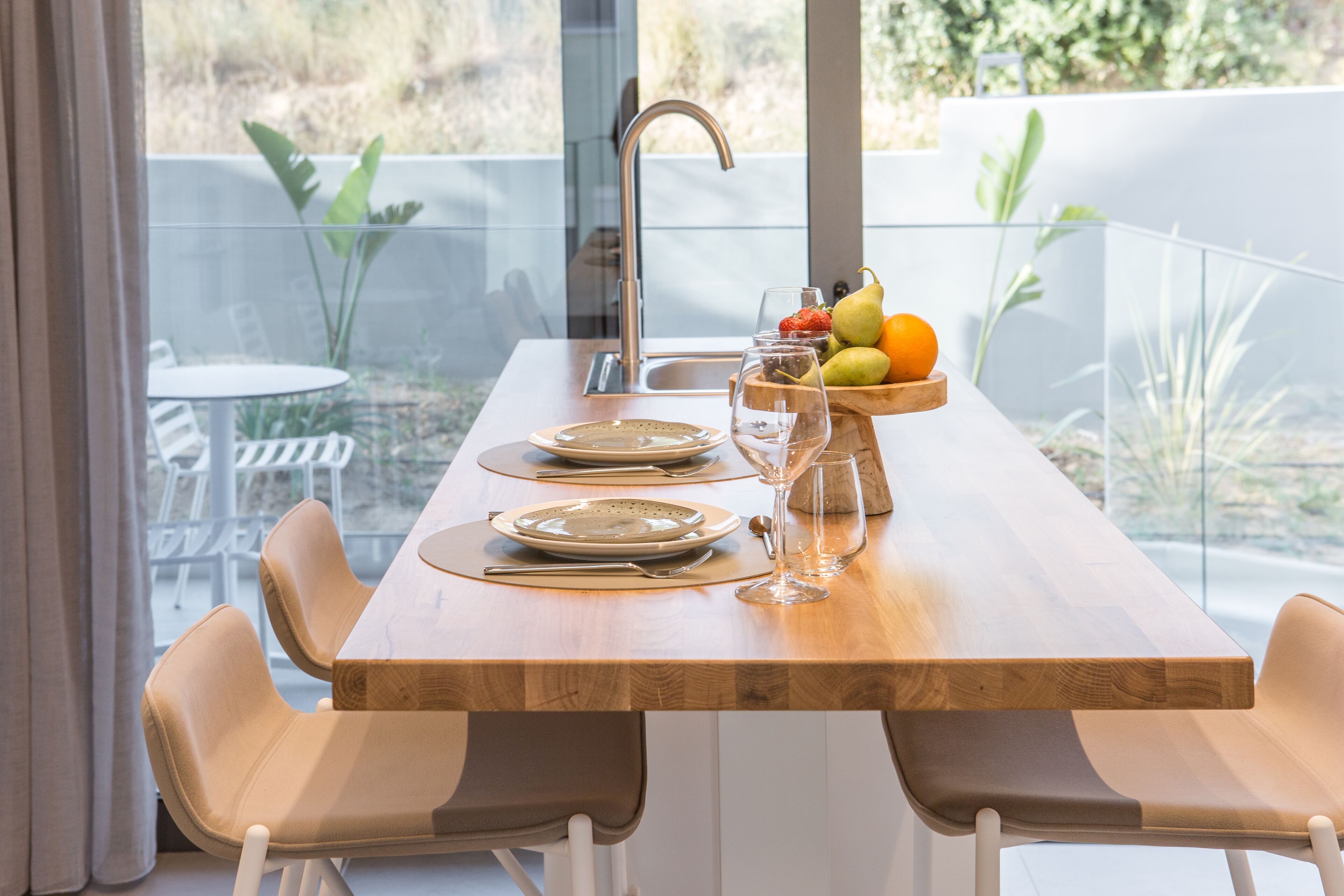 A dining table set with plates, cutlery, and a fruit bowl.