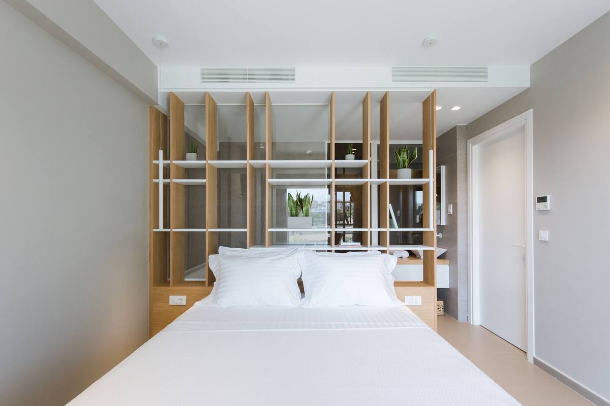 Un dormitorio moderno con una cama grande, estanterías empotradas y una planta en maceta a la vista.