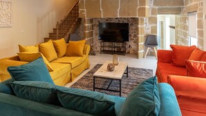 A living room with a stone fireplace, a TV, and a staircase.