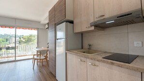 A modern kitchen with wooden cabinets, a built-in refrigerator, a sink, and a dining area with a table and chairs. - Les Pradels by Interhome (Cavalaire)