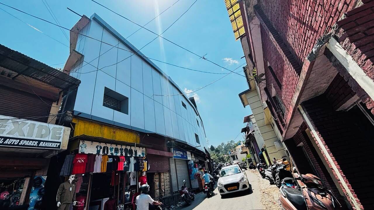 Vista de la calle con un edificio que tiene una tienda en la planta baja y viviendas en lo alto.