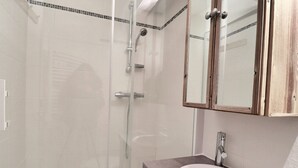 A bathroom with a glass shower enclosure, a sink with a mirror above it, and wooden cabinets. - Comfortable 2 Rooms + Cabin, Pets Allowed, Ski-in/Ski-out (La Tania)