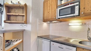 A compact kitchen with wooden cabinets, a built-in microwave, a dishwasher, and a sink. - Comfortable 2 Rooms + Cabin, Pets Allowed, Ski-in/Ski-out (La Tania)
