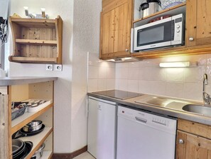 A compact kitchen with wooden cabinets, a built-in microwave, a dishwasher, and a sink.