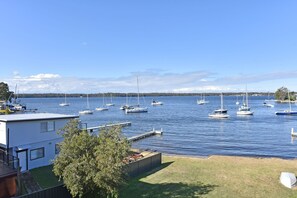 A marina with multiple sailboats docked, a grassy area with a building, and a clear sky. - Sunshine Shores Absolute Waterfront (Sunshine)